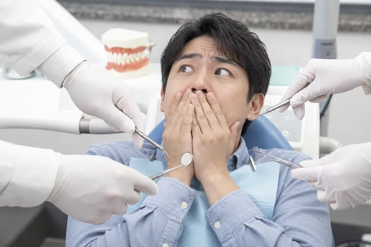 진료 기구를 든 손들 사이에서 놀라 입을 가린 남성