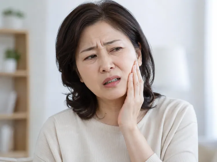 볼을 감싸 쥐고 아파하는 여성
